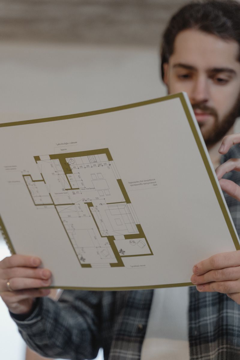 An architect reviewing a house floor plan on a drafting table